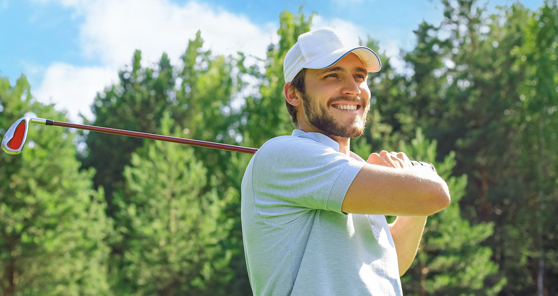 A man is swinging a golf club on a golf course.