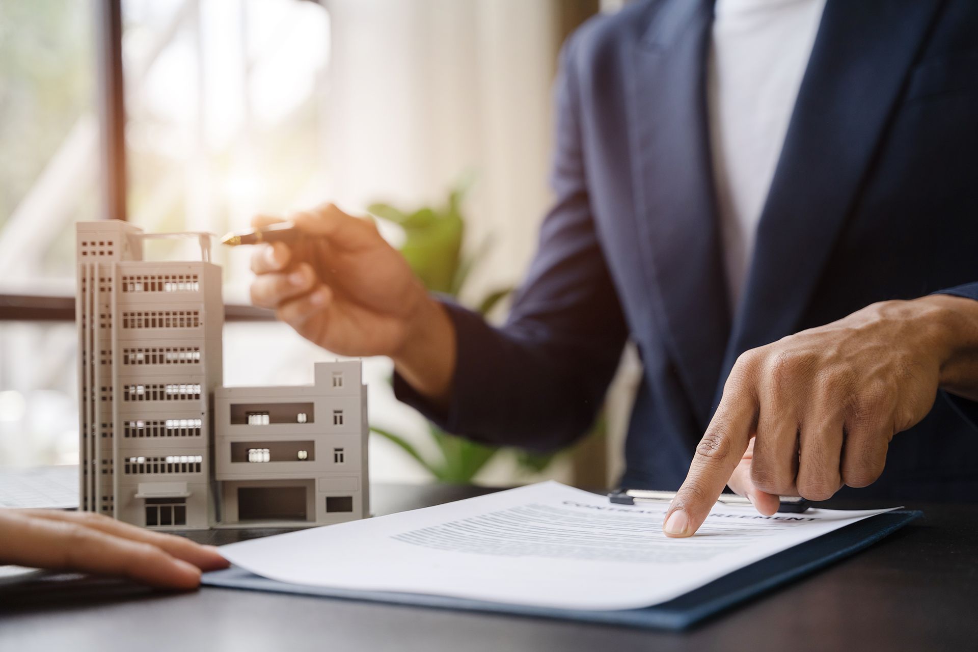 A woman is pointing at a model of a building on a piece of paper.