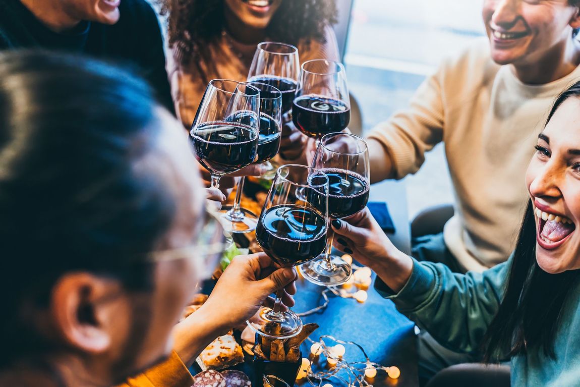 A group of people are toasting with wine glasses at a table.