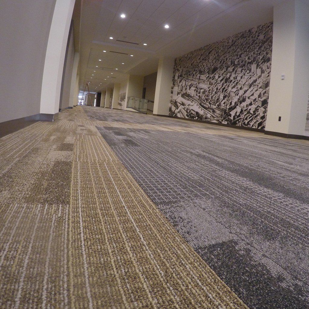 A hallway with a carpeted floor and a wall with a picture on it.