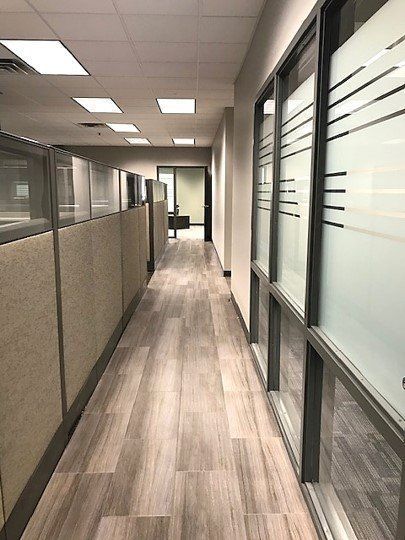 A long hallway with cubicles and windows in an office building.