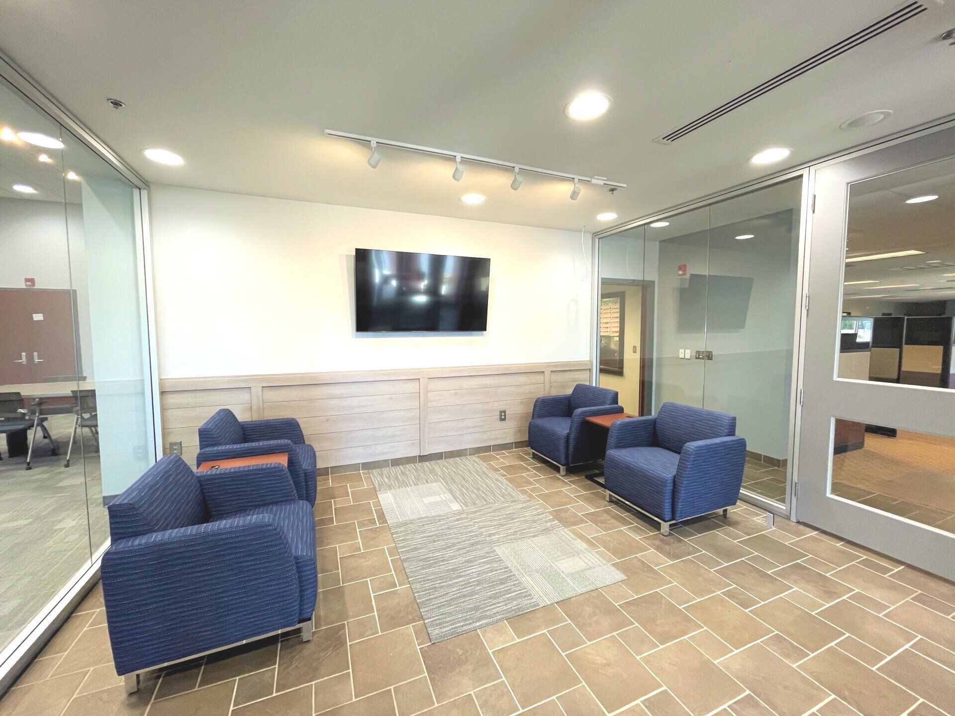 A living room with chairs and a television on the wall.