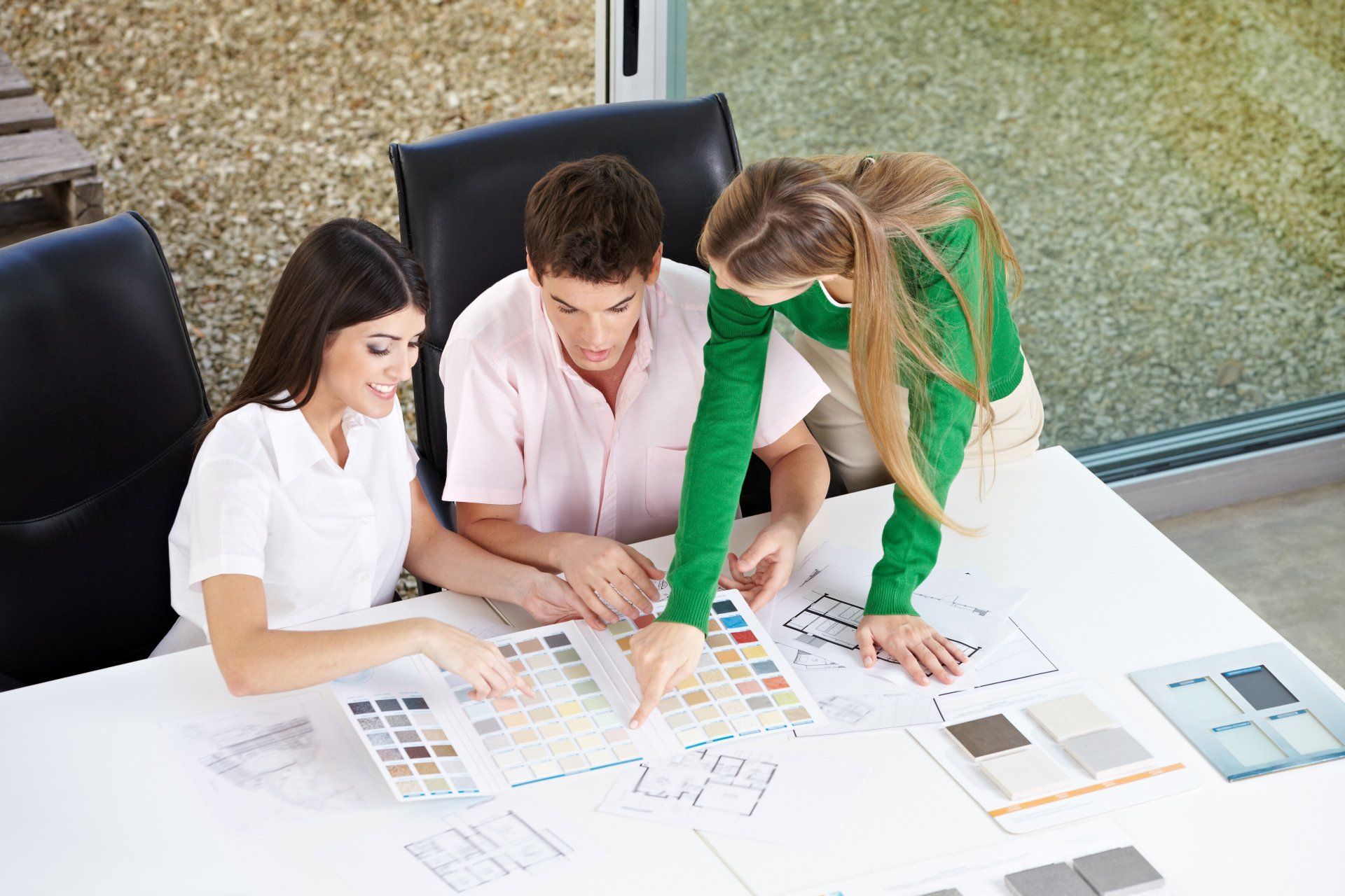 A group of people are sitting at a table looking at a color palette.