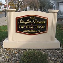 Sign for Stauffer-Breznik Funeral Home, with address 412, in cream with a black and gold plaque.