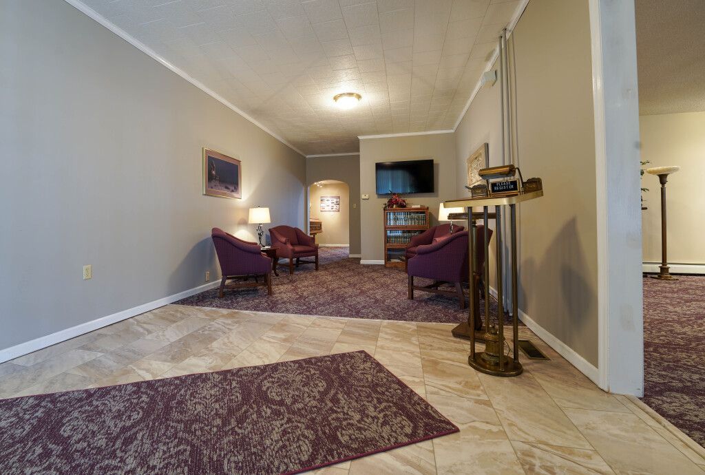Lounge with gray walls, purple chairs, rug, TV, and vintage floor lamp.