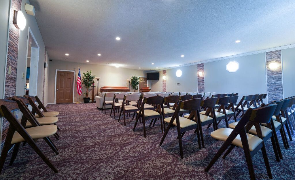Rows of chairs in a funeral home chapel with ornate purple carpet.