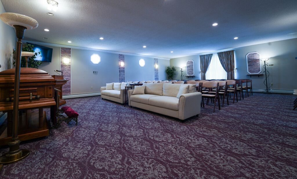 Interior of a funeral home with couches, chairs, and a casket, mauve carpet.