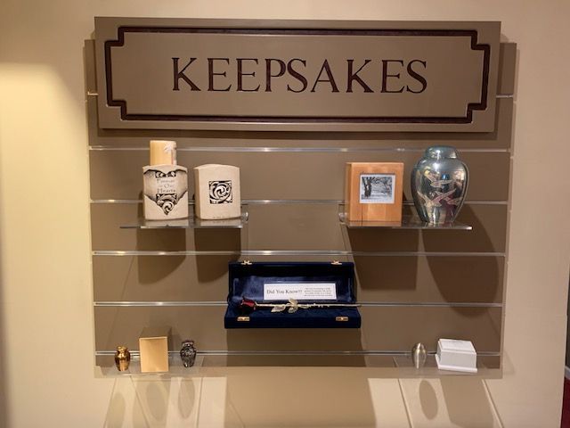 Display of keepsakes: urns, a photo frame, and jewelry, in a retail setting.