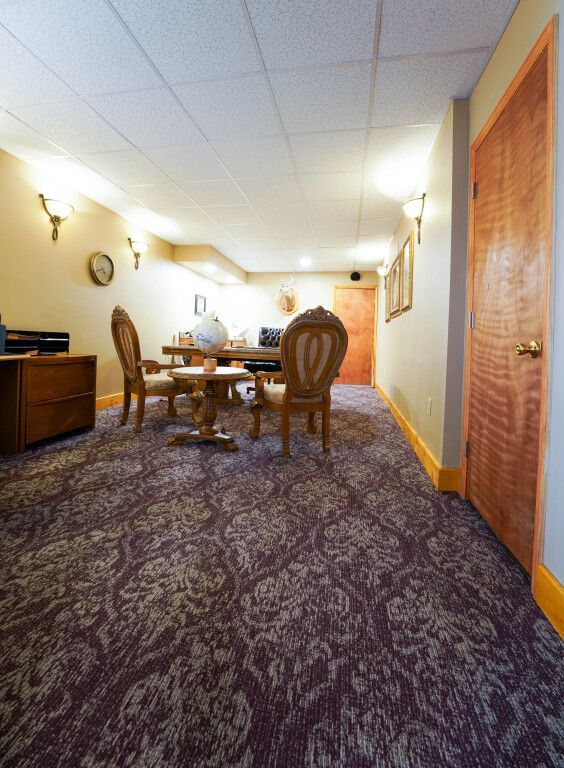 Room with ornate carpet, a table with chairs, and a wooden door.