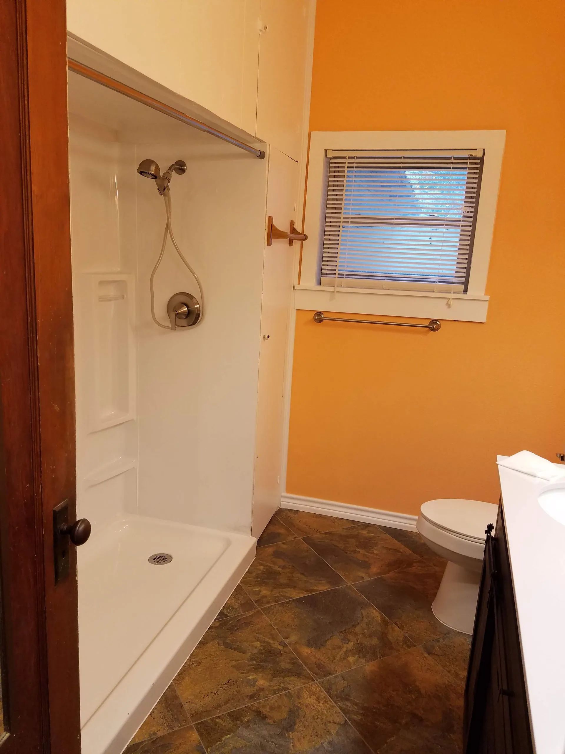A bathroom with a toilet a shower and a window
