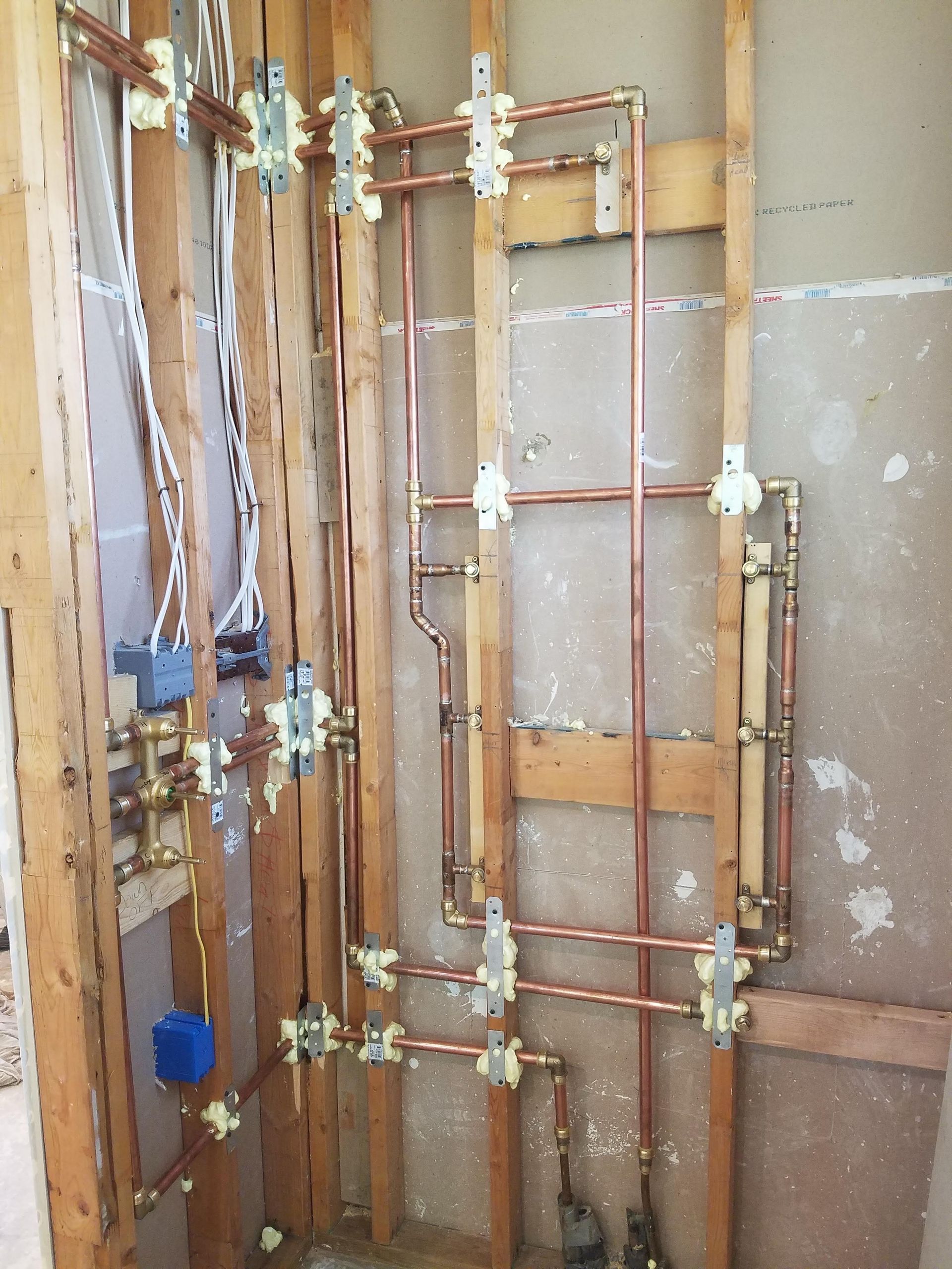 Copper pipes are being installed in a bathroom under construction