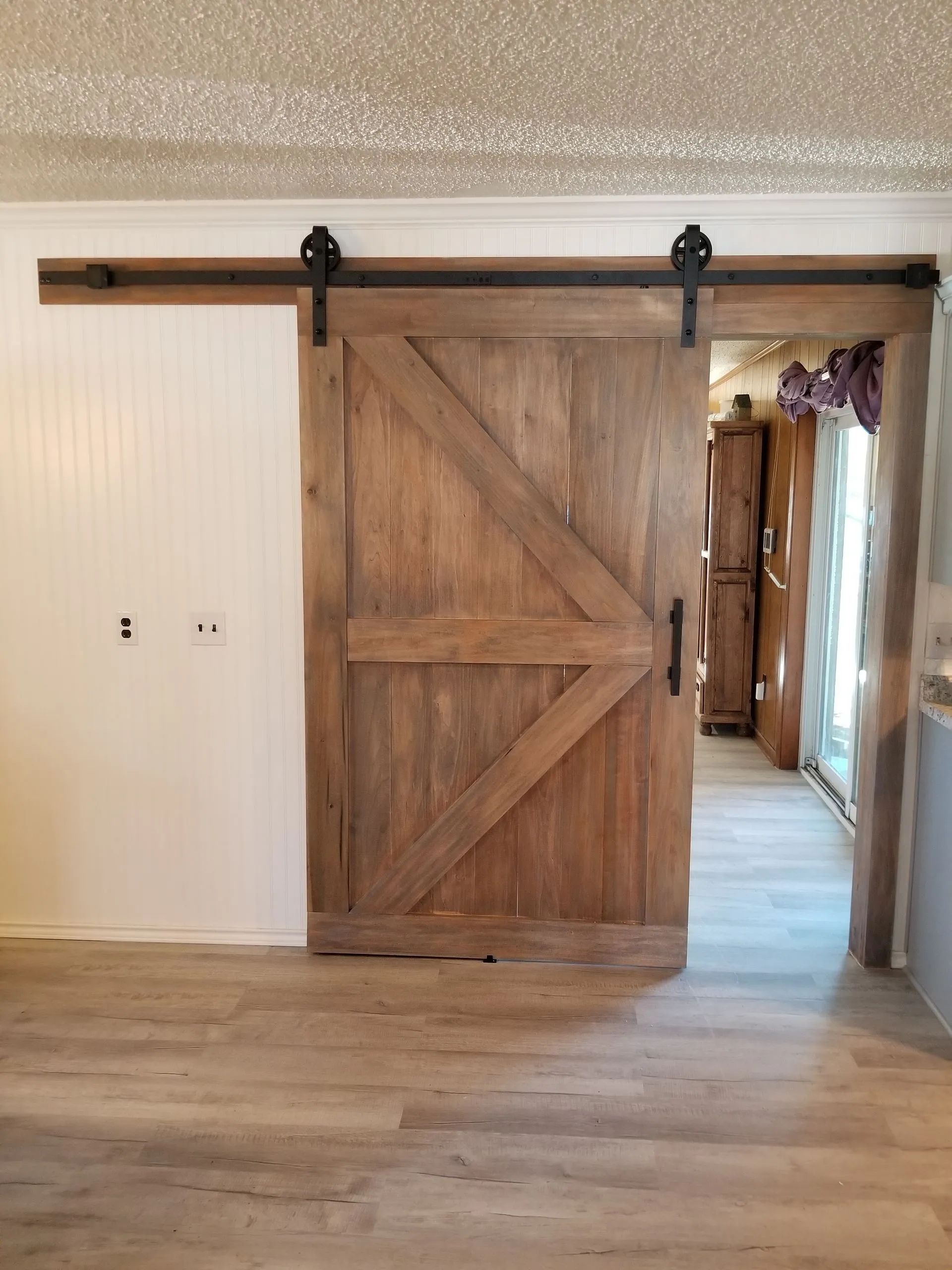 A wooden sliding barn door is open in a living room.