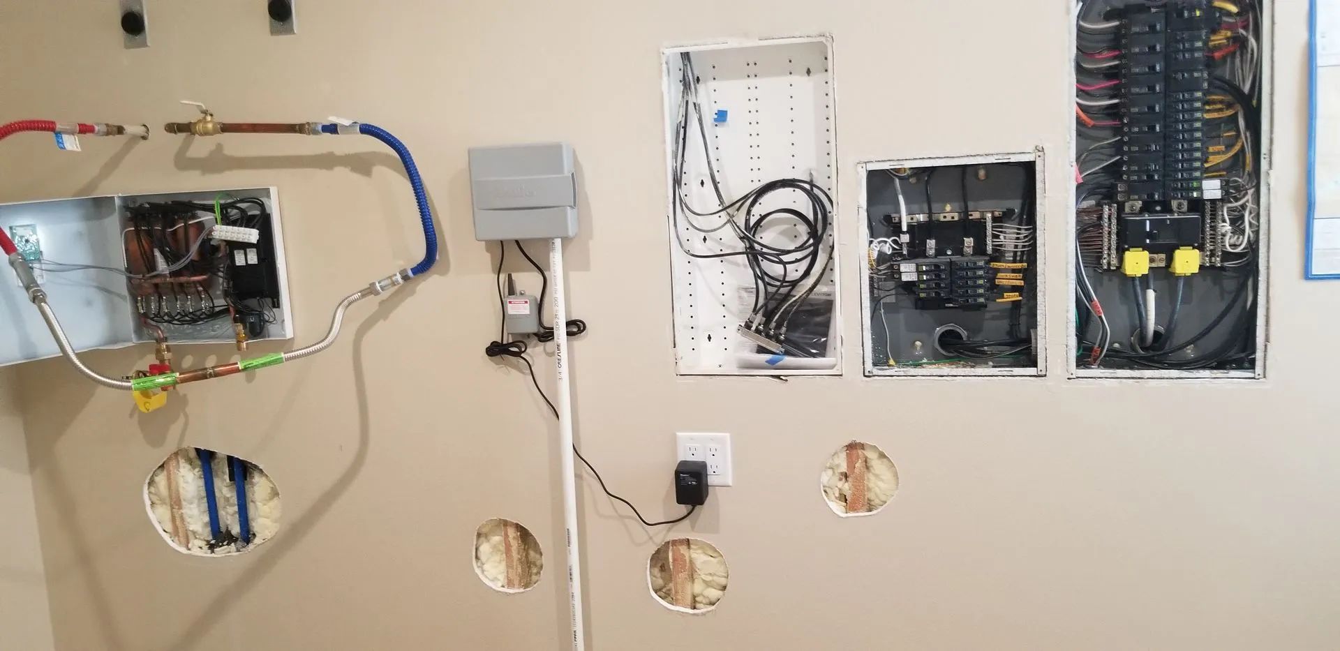 A wall with electrical boxes and wires hanging from it.