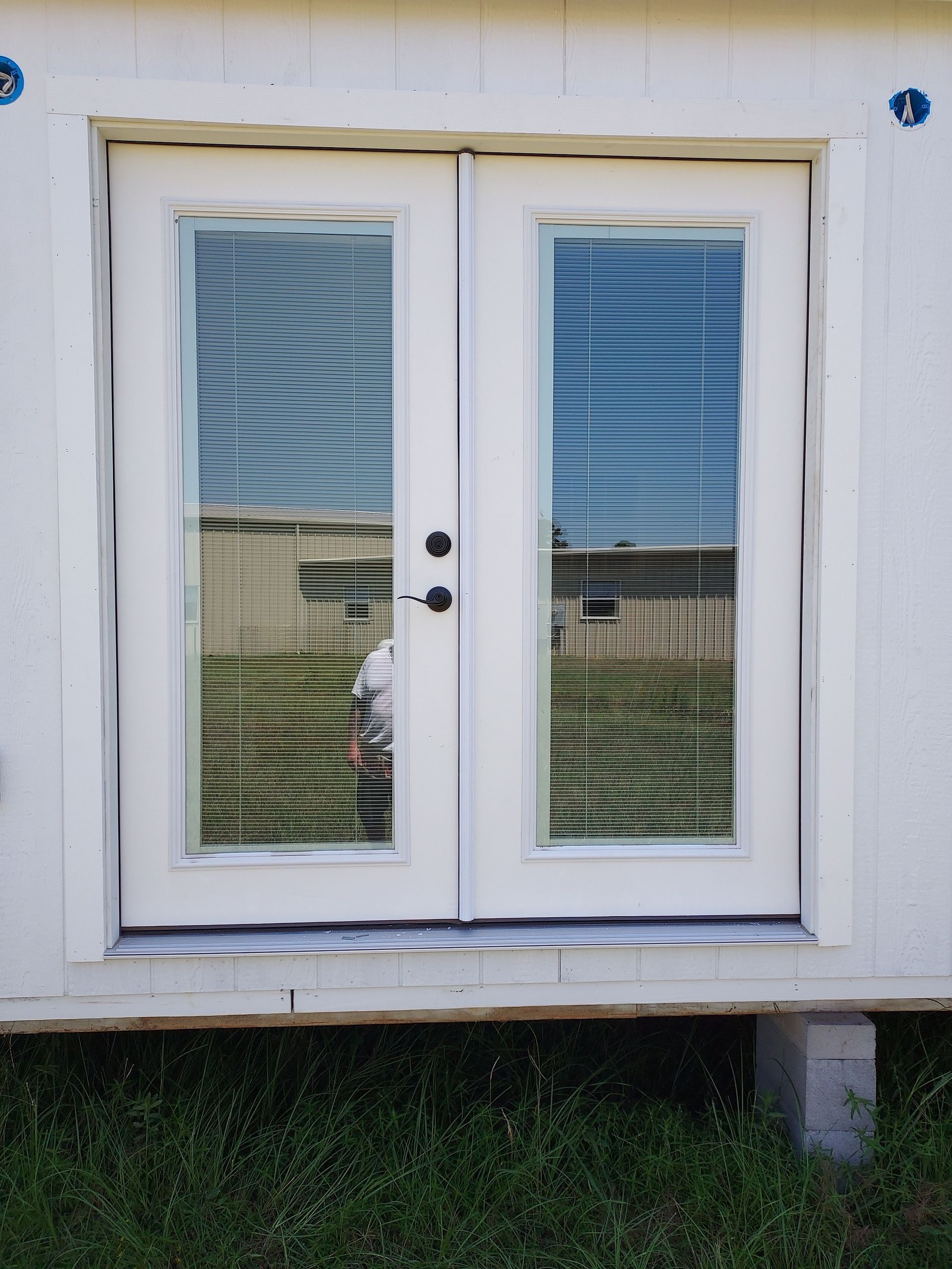 A white door with a reflection of a house in the window