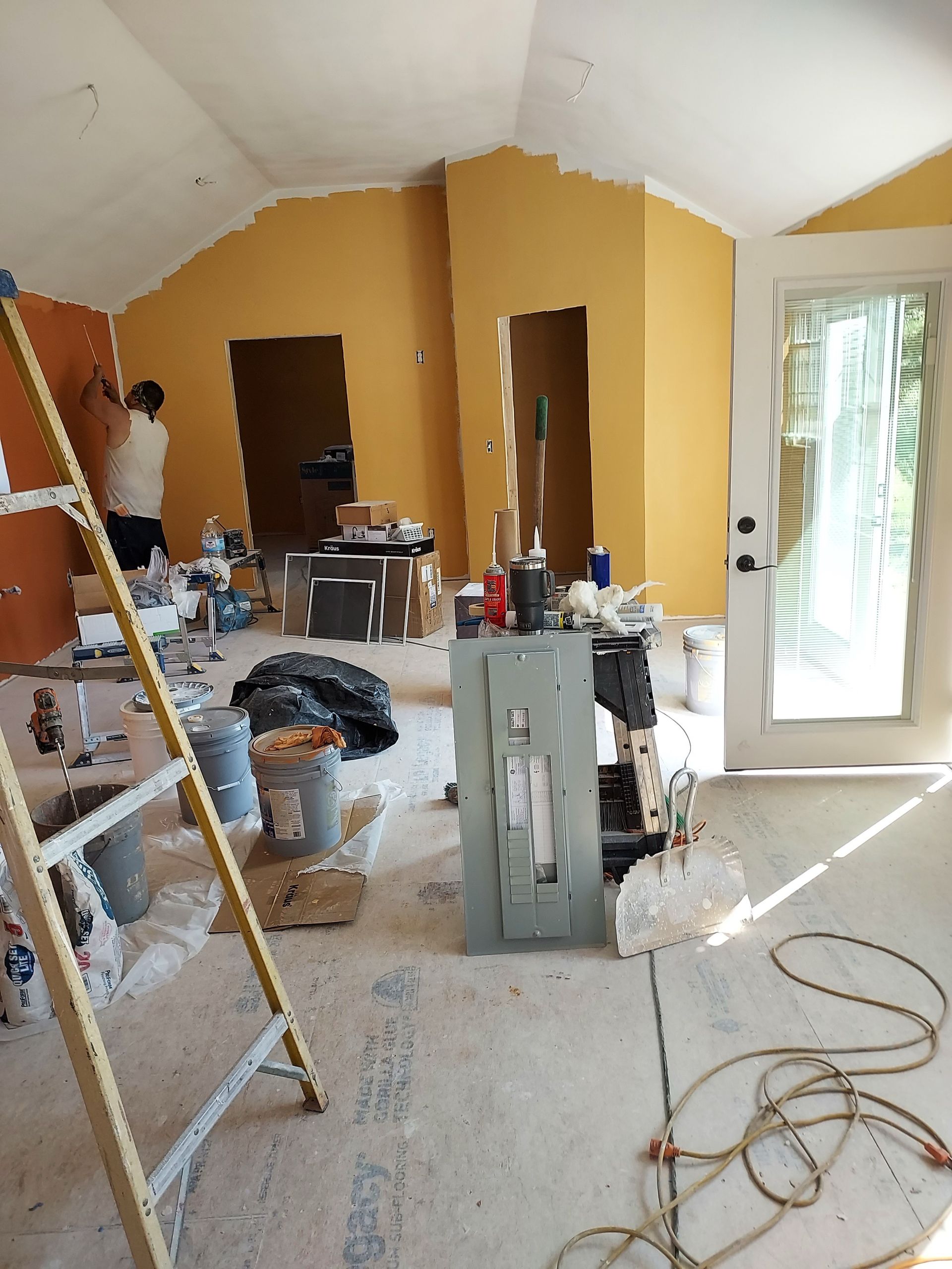 A room that is being painted with a ladder in the foreground