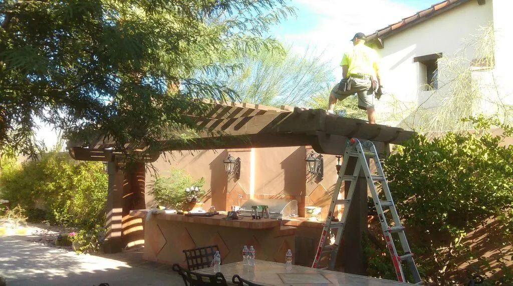A man is standing on a ladder on top of a pergola.