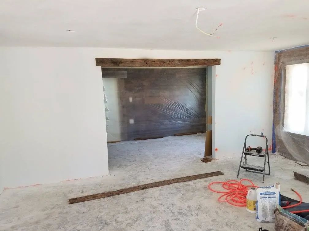 A living room under construction with a wooden beam in the middle of the room.