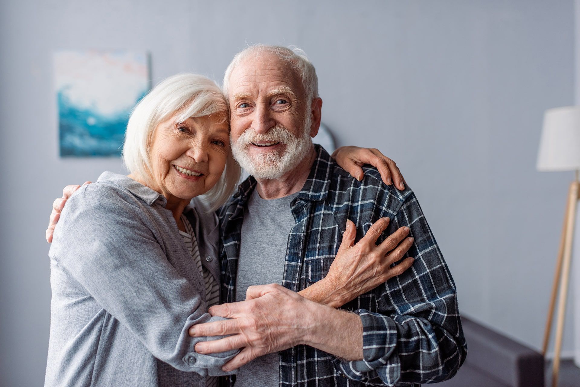 An elderly couple holds each other.