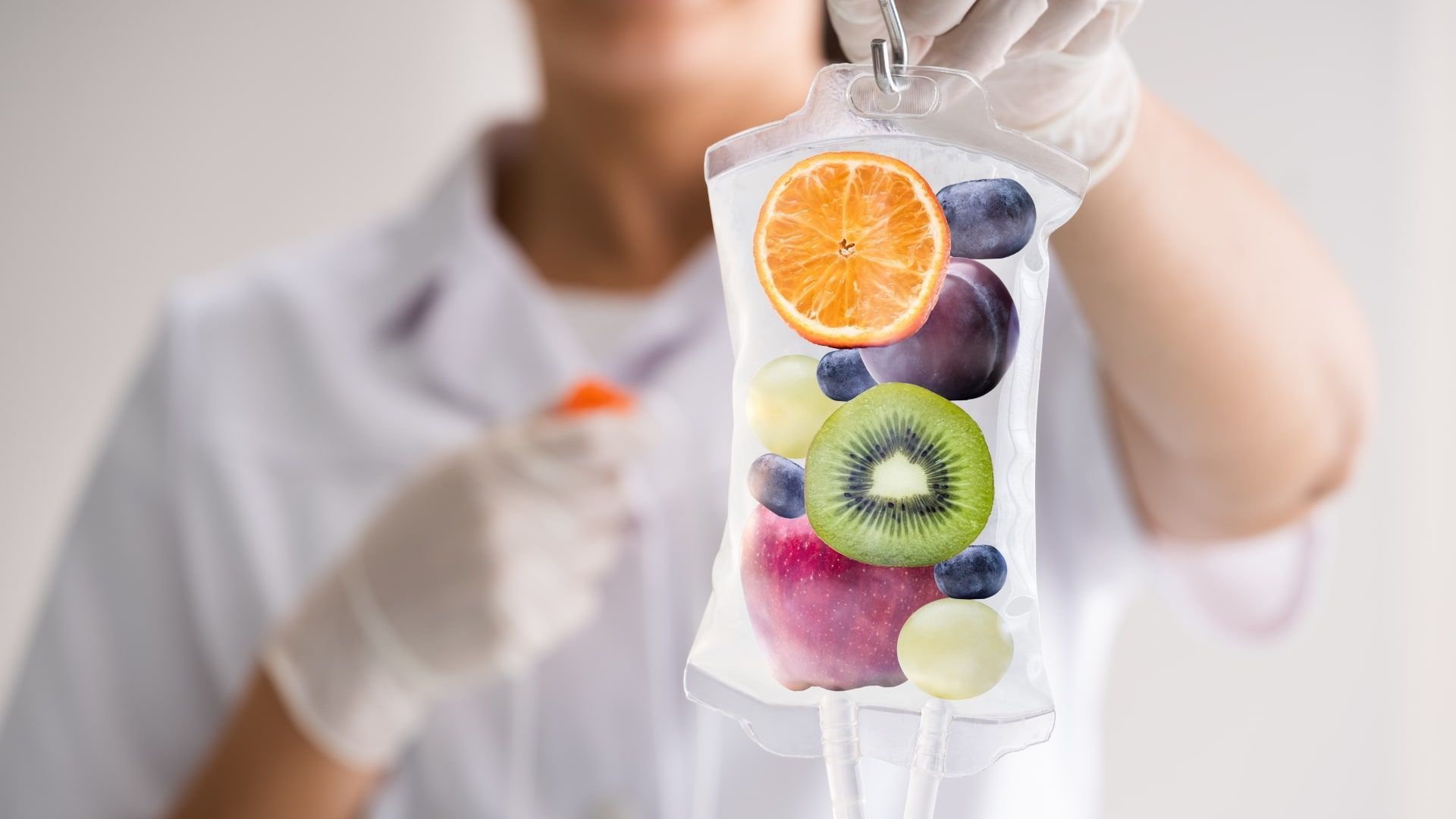 A nurse holding an IV Bag full of fruits meant to represent its nutrients.