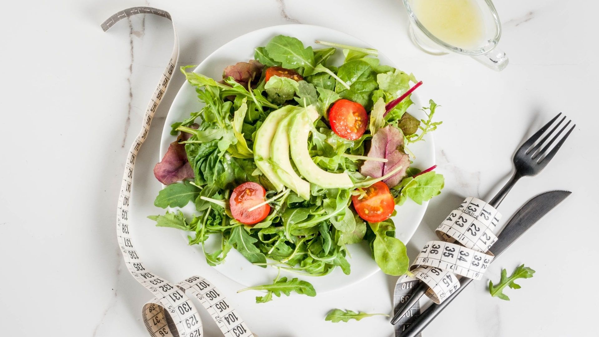 A salad and measuring tape, meant to signify weight loss and eating healthy.