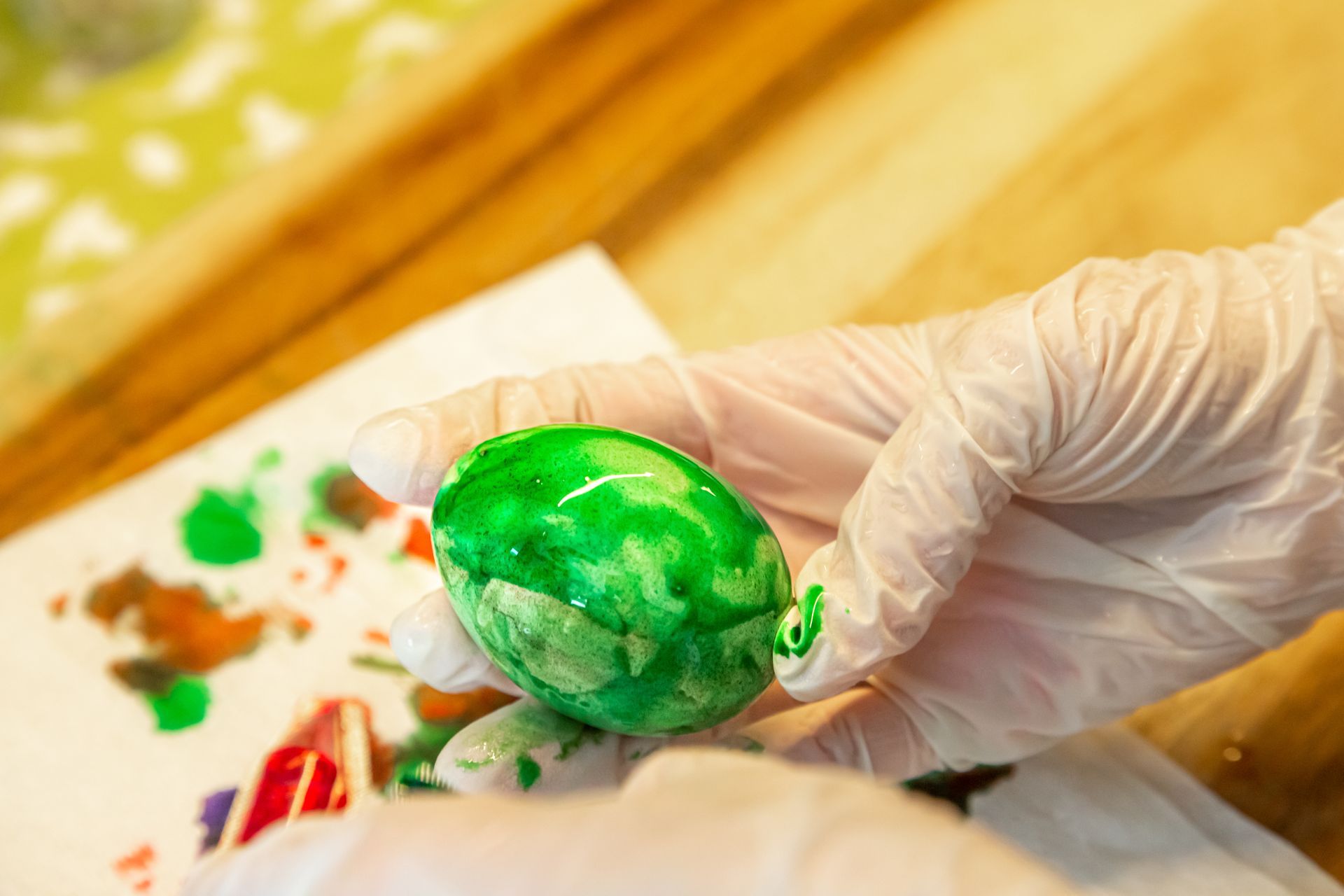 A person is holding a green egg in their hand.