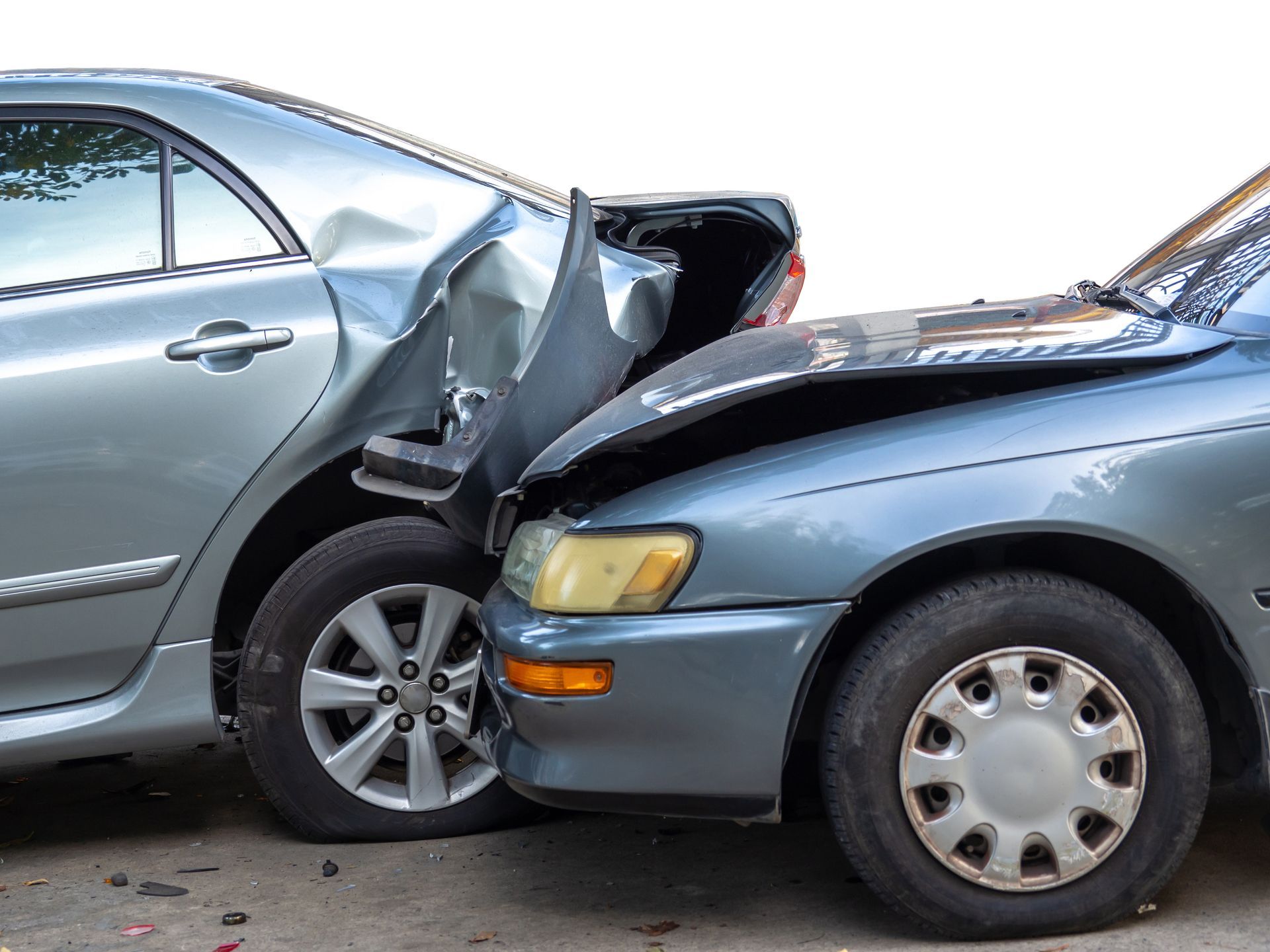 Two cars in a front-end collision, with the silver car rear-ending the blue car.