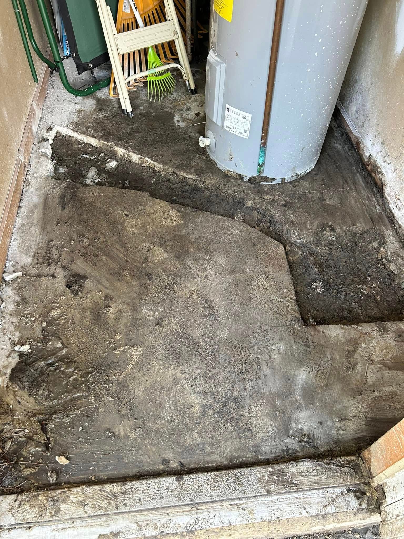 An unfinished dirt floor area with a water heater installed in the corner next to a yellow tool.