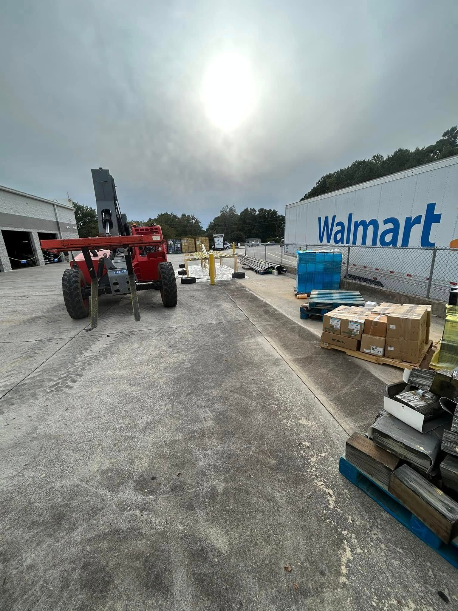 A red forklift parked near a Walmart trailer in a loading area with stacked cardboard boxes and pallets.