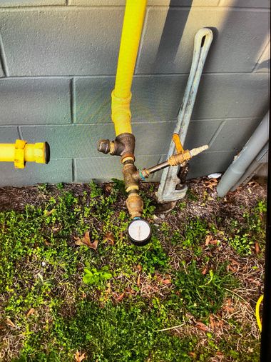 A metal ActivFlo water conditioner installed in a white pipe line, situated in an open, dirt-filled trench.