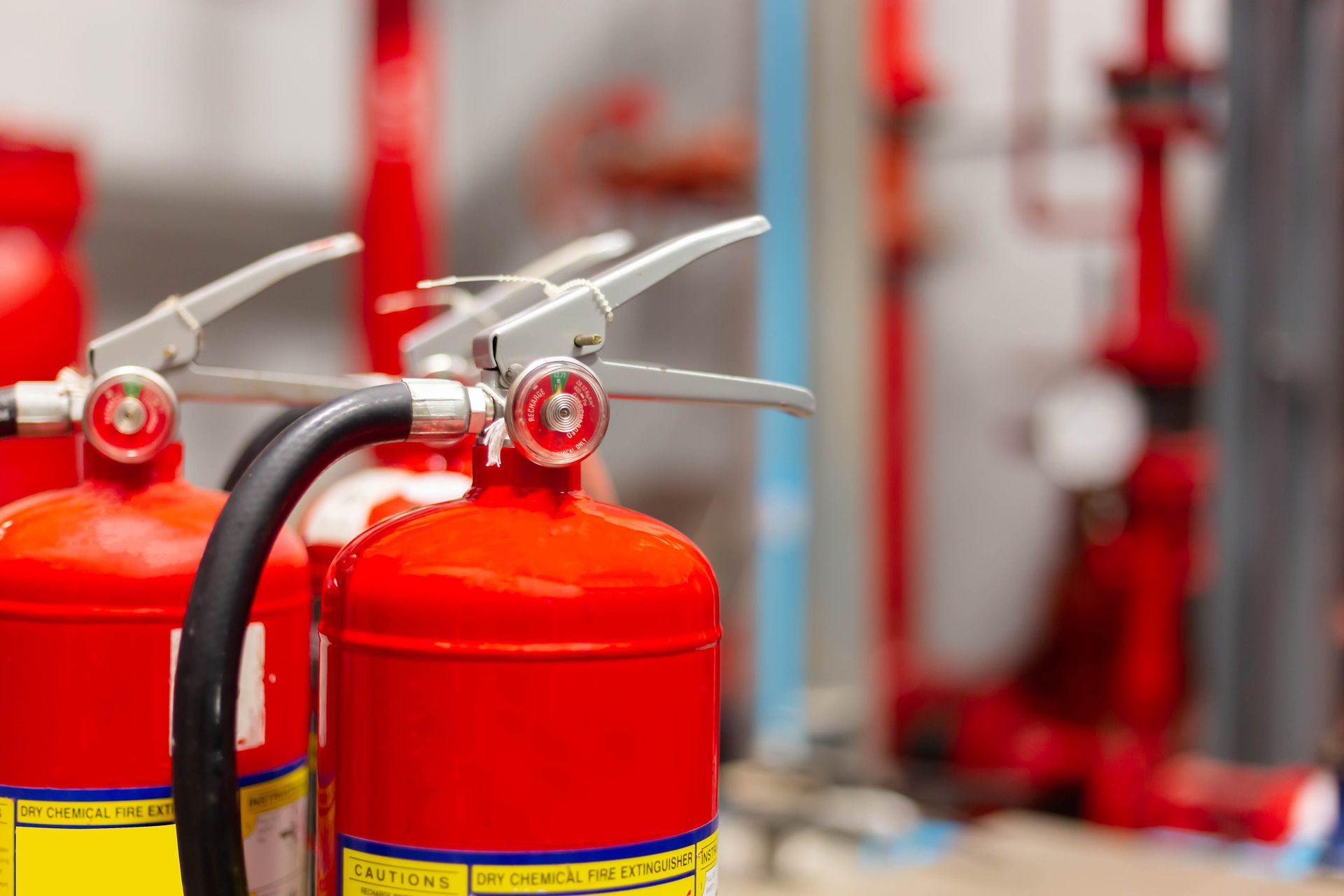 Red fire extinguishers with hoses in a row, close-up indoors