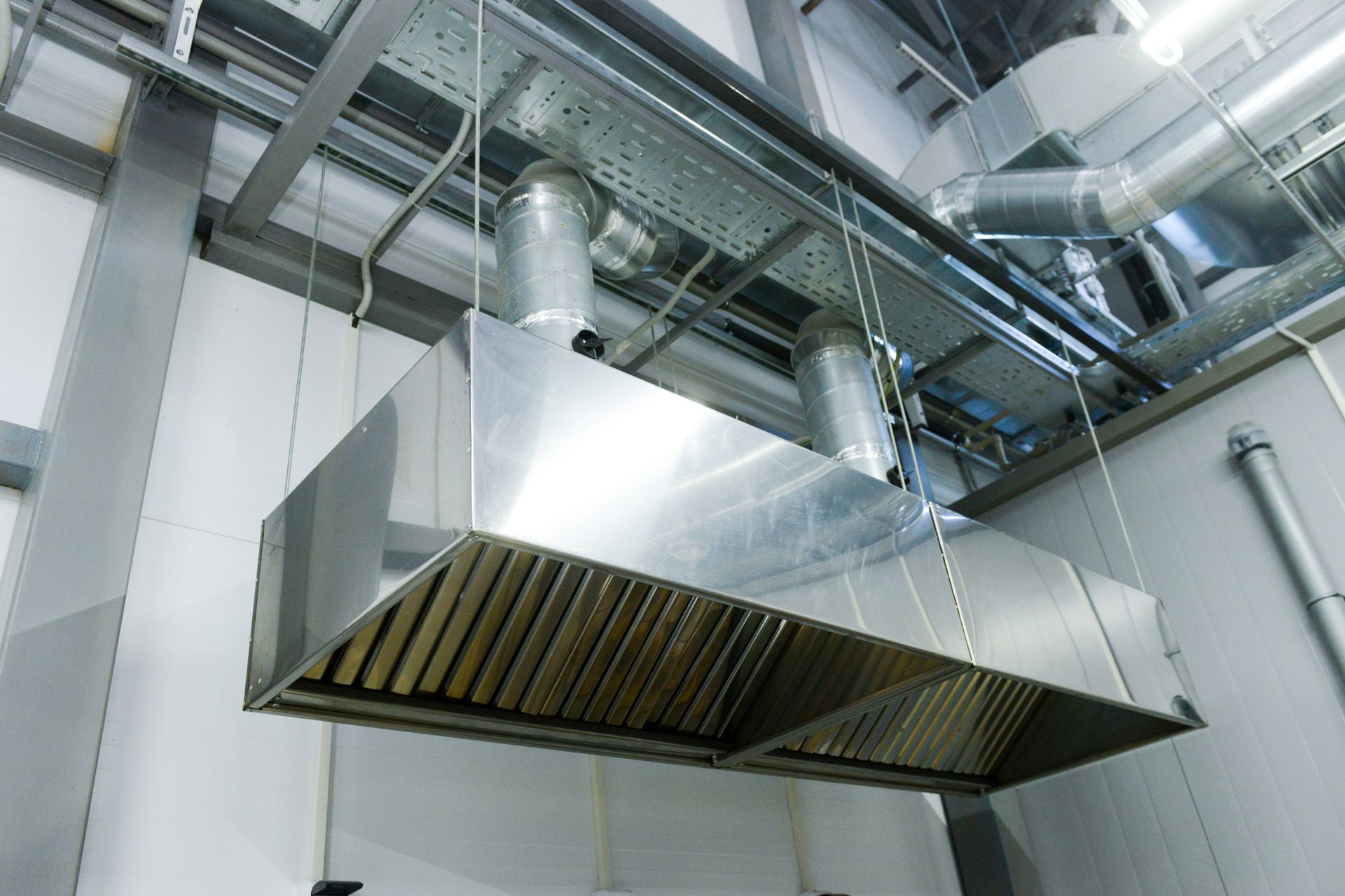 Stainless steel kitchen ventilation hood and ductwork in an industrial kitchen ceiling
