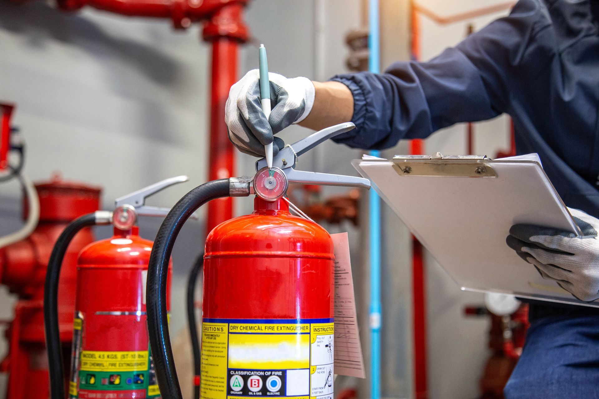 Person servicing a red fire extinguisher with a clipboard in a safety equipment room