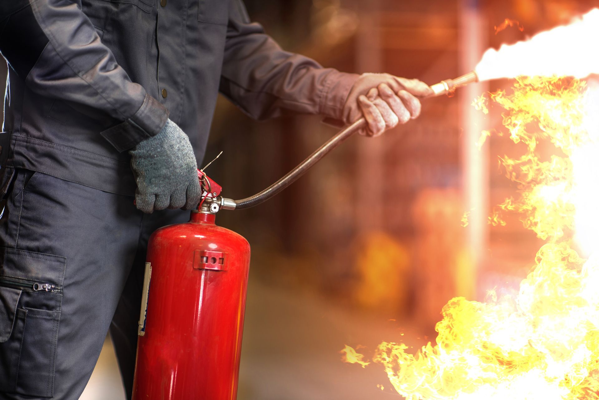 Person using a red fire extinguisher to spray flames in a dark setting