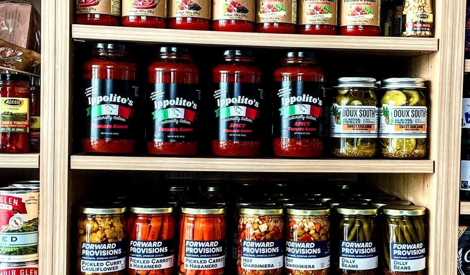 A shelf filled with jars of tomato sauce and pickles.