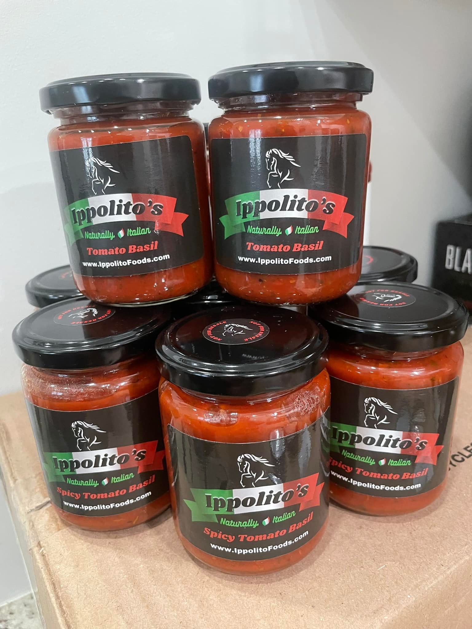 A bunch of jars of tomato sauce are stacked on top of each other on a table.