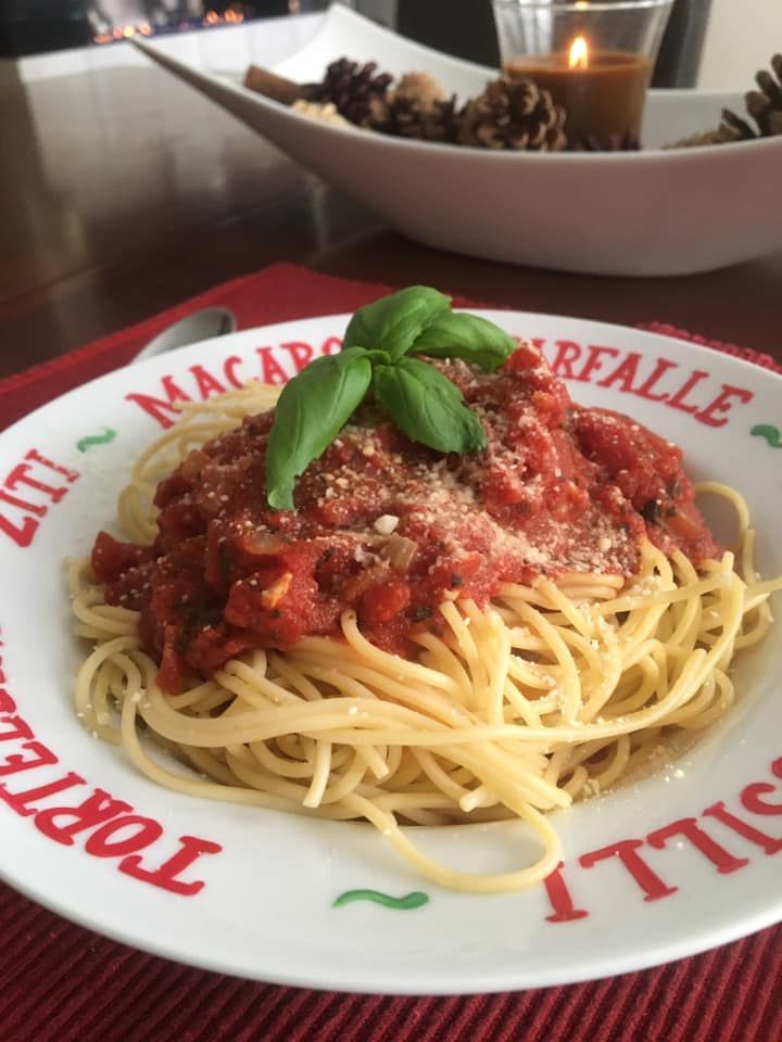 A plate of spaghetti with tomato sauce and basil on a table