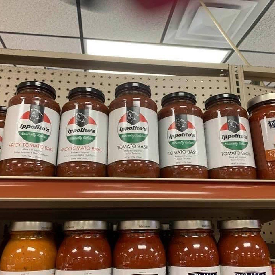 Several jars of tomato sauce are lined up on a shelf