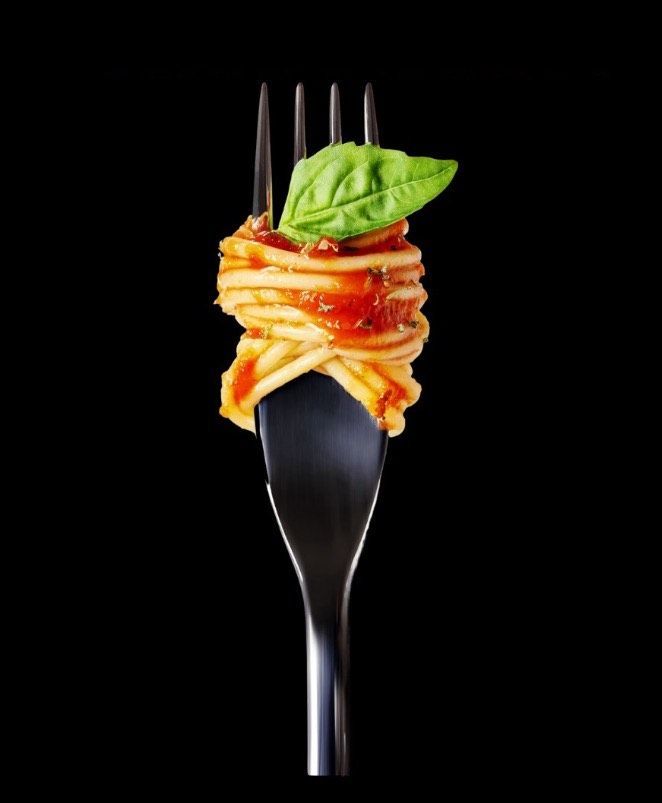 A black fork with spaghetti and basil on it