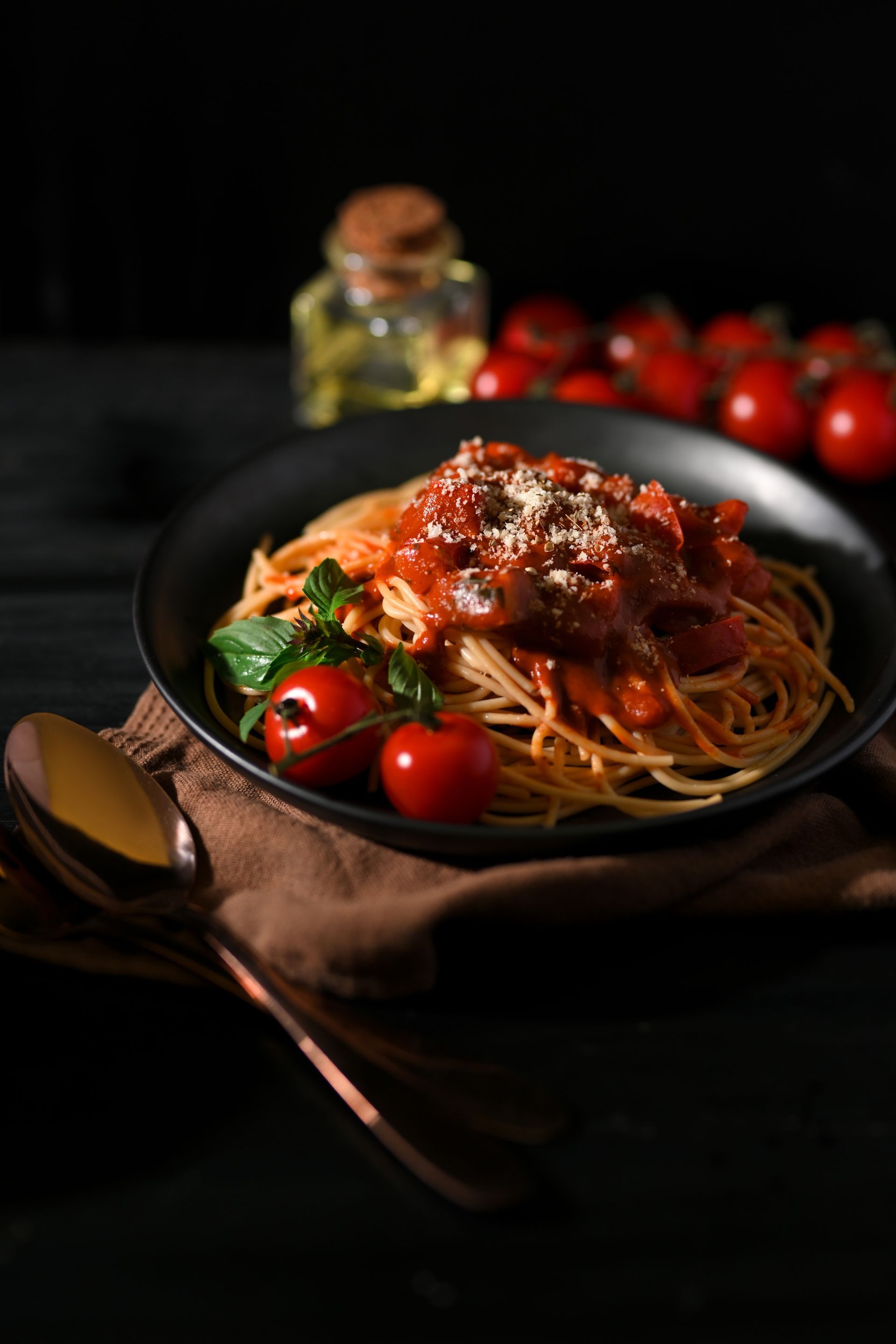 A bowl of spaghetti with meat sauce and tomatoes on a table.