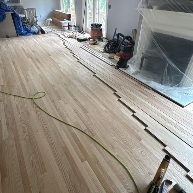 Wooden floor installation in progress indoors, with tools and materials visible.