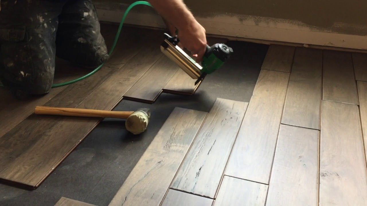 A construction worker is laying a tile floor in a room.