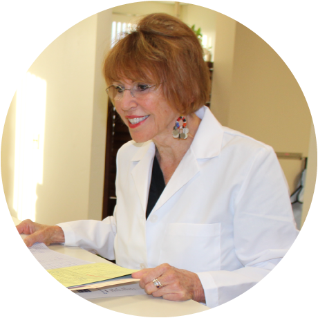 Dr. Roberta in a lab coat is sitting at a desk