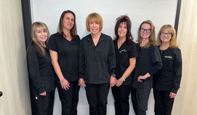 A group of nurses wearing masks and scrubs are posing for a picture.