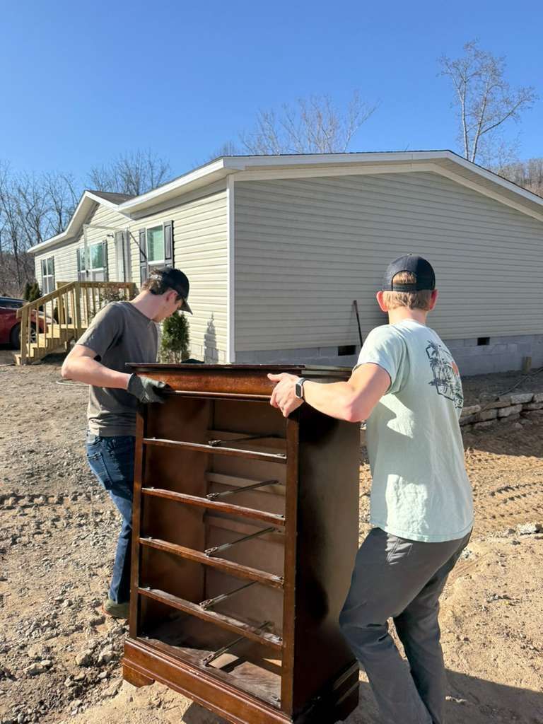 Two men carrying a bookcase to refurbished house.