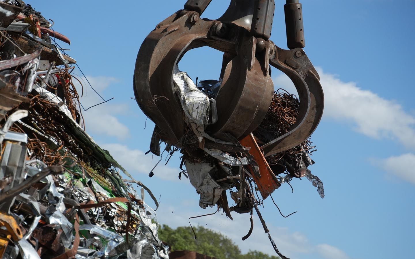 A claw is lifting a pile of scrap metal into the air.