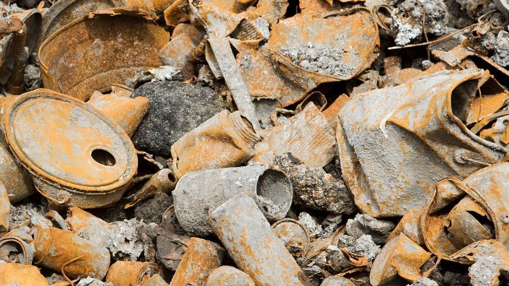 A pile of rusty cans and bottles on the ground.