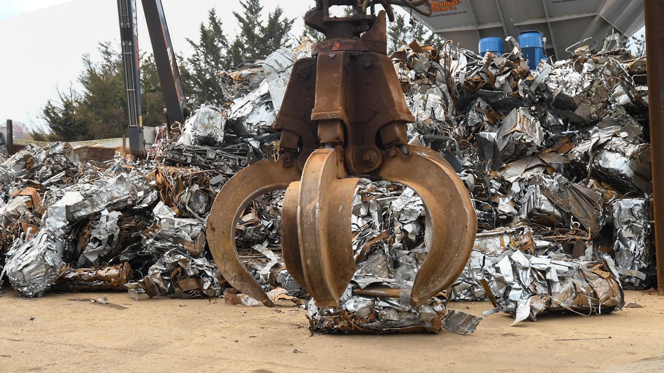 A large metal claw is sitting in front of a pile of scrap metal at Benfleet Scrap depot