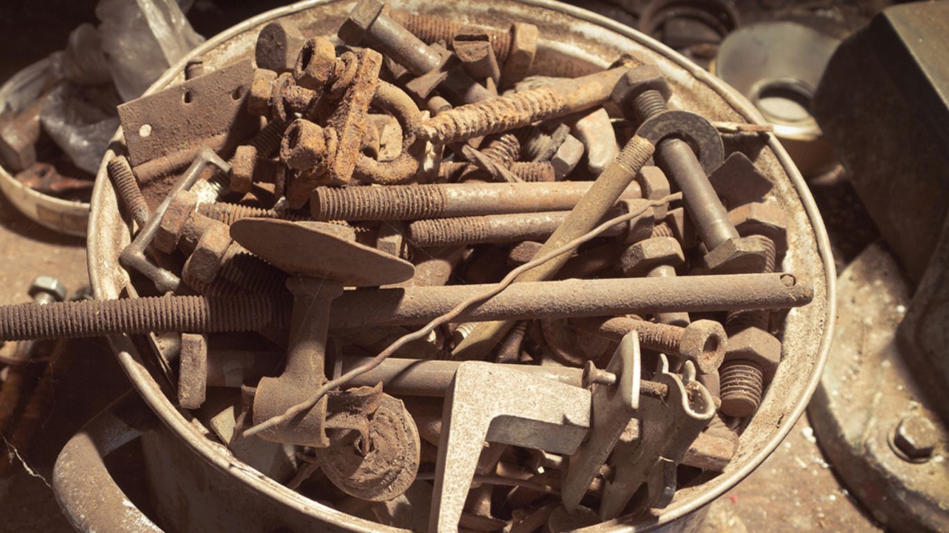 A bowl filled with rusty metal items including nuts and bolts