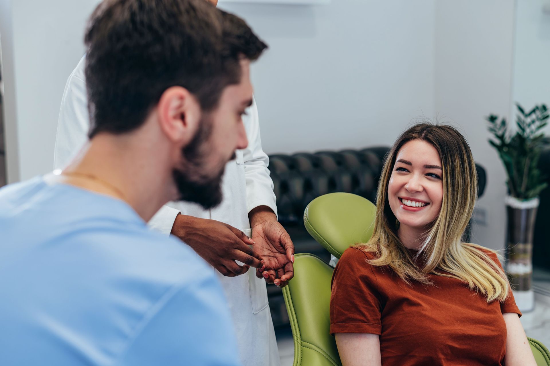 Dentist talking to a patient in an examination room. The patient smiles, and the dentist looks at her.
