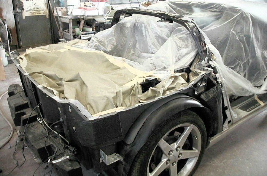 A car is wrapped in plastic and sitting in a garage.